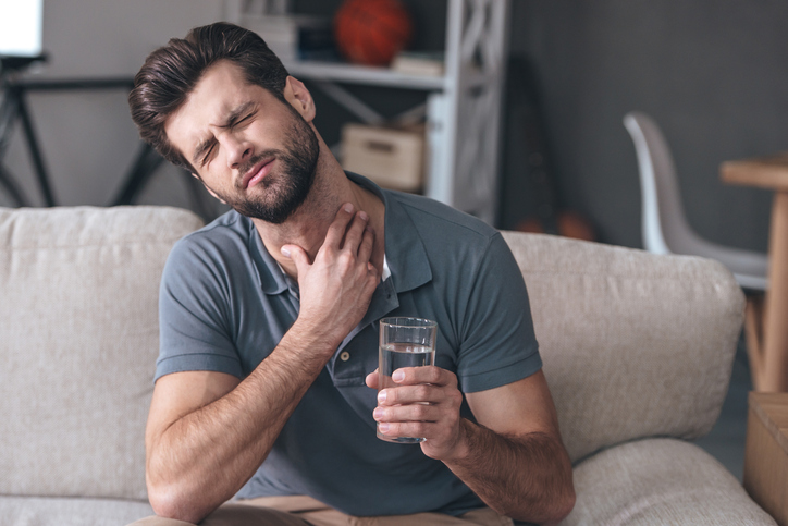 Un homme souffre d'un mal de gorge aggravé par l'eau qu'il boit