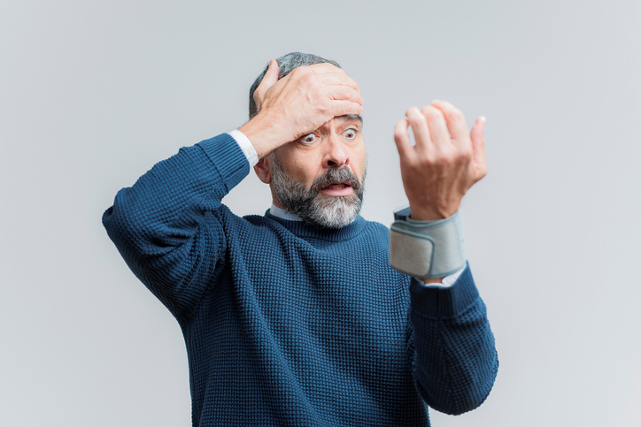 Un homme âgé mesure sa tension artérielle à son poignet et est horrifié à la vue d'un tensiomètre.