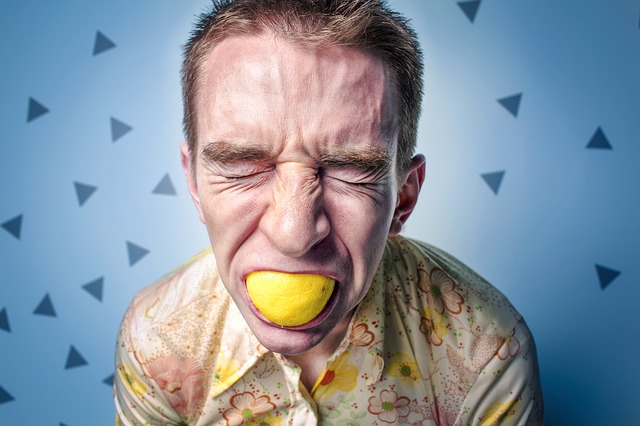 l'homme avec le citron dans la bouche a une expression faciale aigre, peut-être une réaction allergique aux agrumes