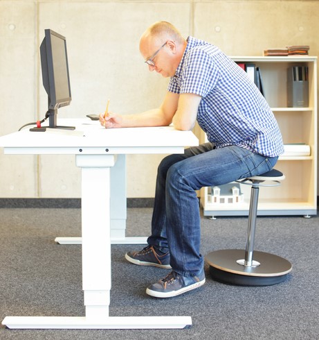 L'homme est assis à un bureau d'ordinateur et a un travail sédentaire