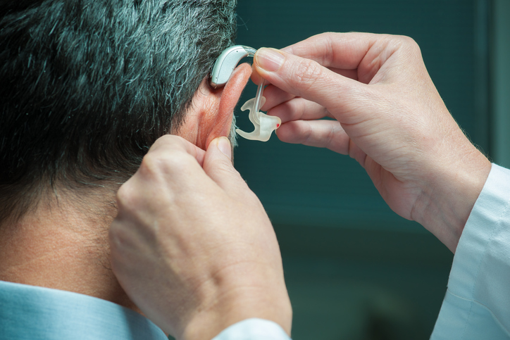 les hommes appliquent un appareil auditif sur l'oreille