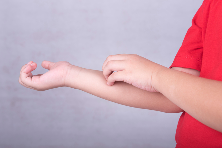 Le bébé se gratte l'avant-bras, se gratte l'avant-bras