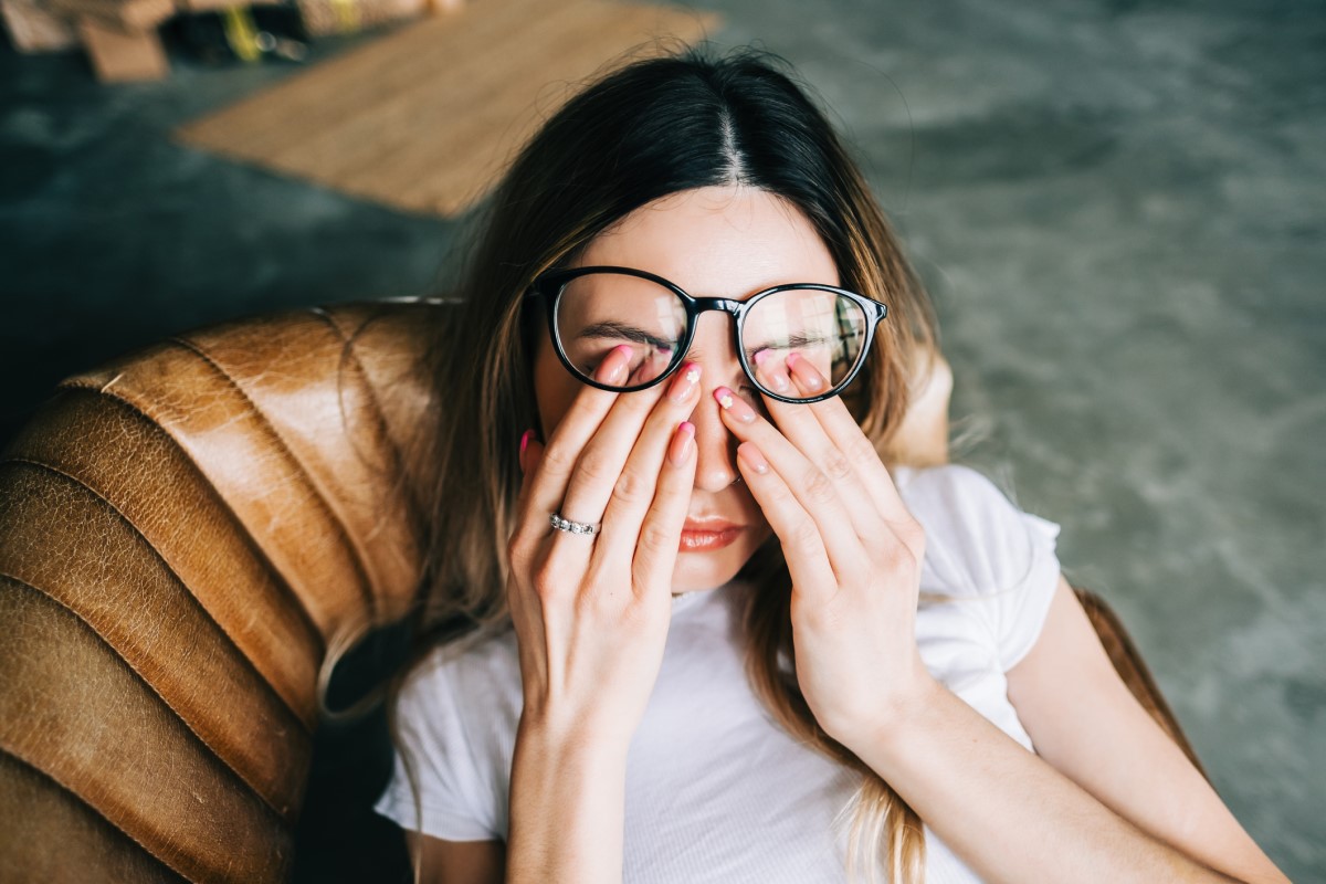 Une femme fatiguée est allongée sur le canapé, se tenant les yeux.