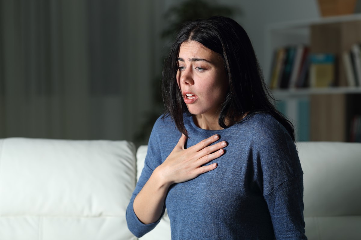 Une femme souffre d'une crise de panique, de peur, s'assoit et se tient la poitrine.