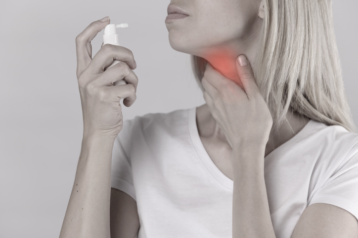 Une femme souffre d'un mal de gorge, d'une inflammation, d'une amygdalite, spray pour traitement topique