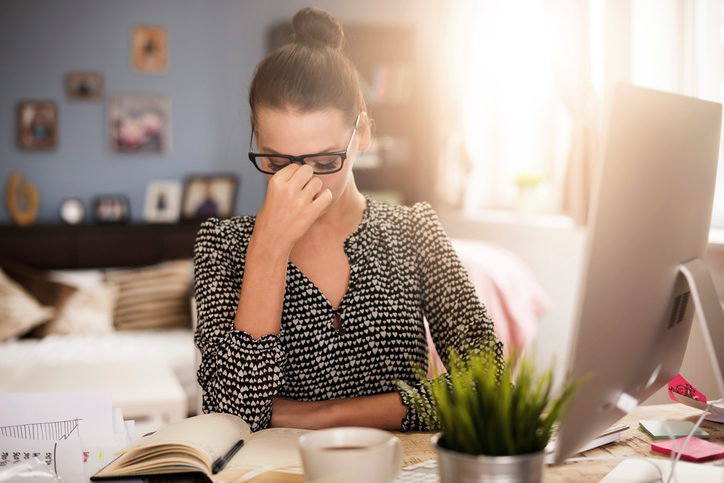 Femme assise à l'ordinateur, fatiguée, les yeux douloureux, travail long