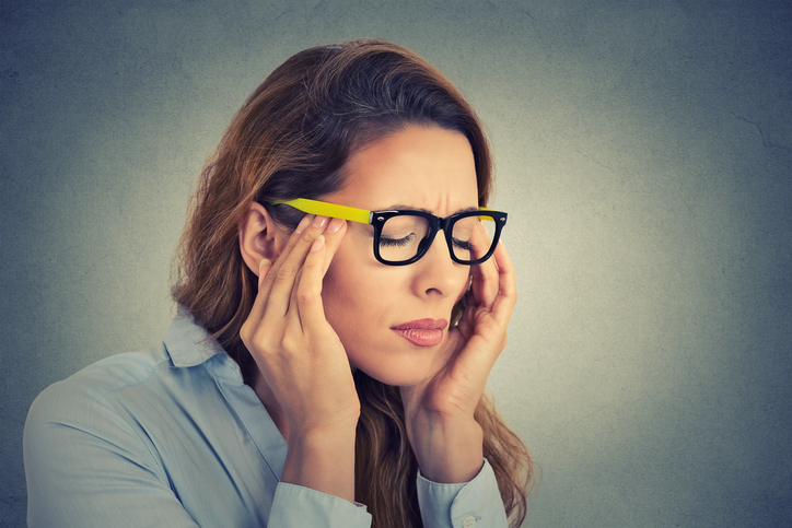 femme avec maux de tête et douleurs oculaires, lunettes jaunes, migraine