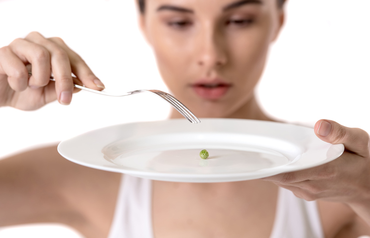 Femme avec des petits pois dans son assiette, restriction alimentaire