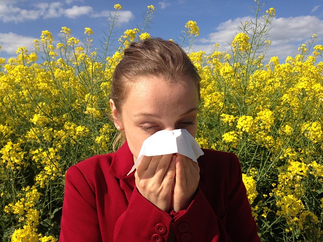 une femme éternue et porte un mouchoir sur son nez elle a le rhume des foins et une allergie au pollen et se trouve dans une prairie