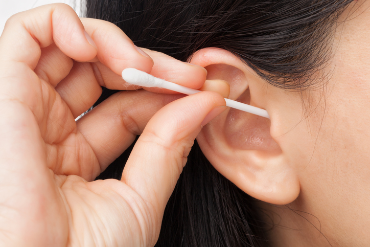 une femme se nettoie l'oreille avec un coton-tige