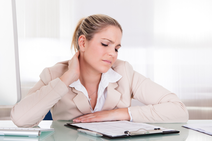 Une femme présente une raideur des muscles de la colonne cervicale, du cou, en raison d'une position assise prolongée, d'un travail sédentaire et du stress au travail.